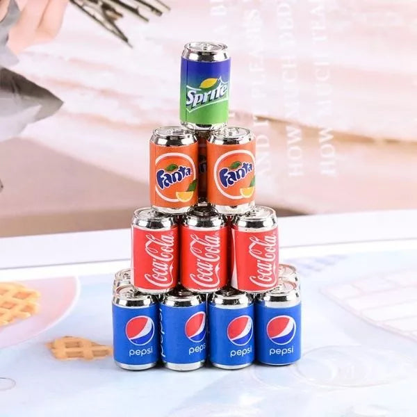 A Miniature Dollhouse Soda Can stacked one upon the other on the floor.