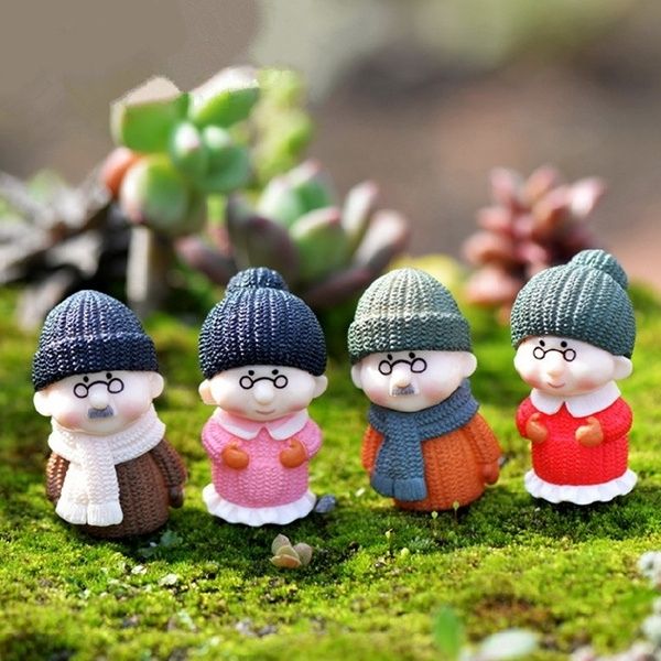 A cute and small 2 Miniature Old Couple Grandparents on a lawn grass of terrarium.