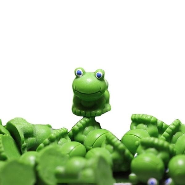 A cute Miniature Toy Frog kept on another Miniature Toy Frog with several similar Miniature Toy Frog in the background.